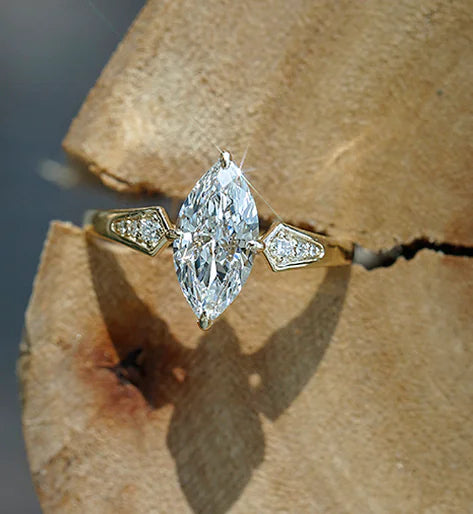 Diamond ring with pear-shaped center stone on a wooden surface