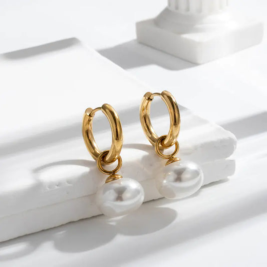Gold hoop earrings on a white surface with soft shadows