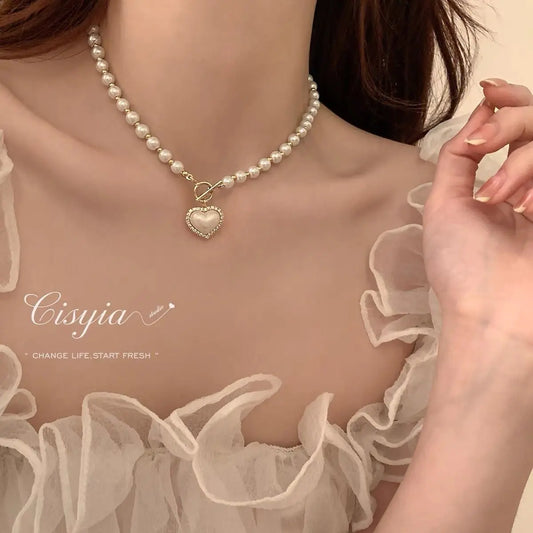 Pearl necklace with a heart pendant worn by a person, with 'Cisyia' branding.