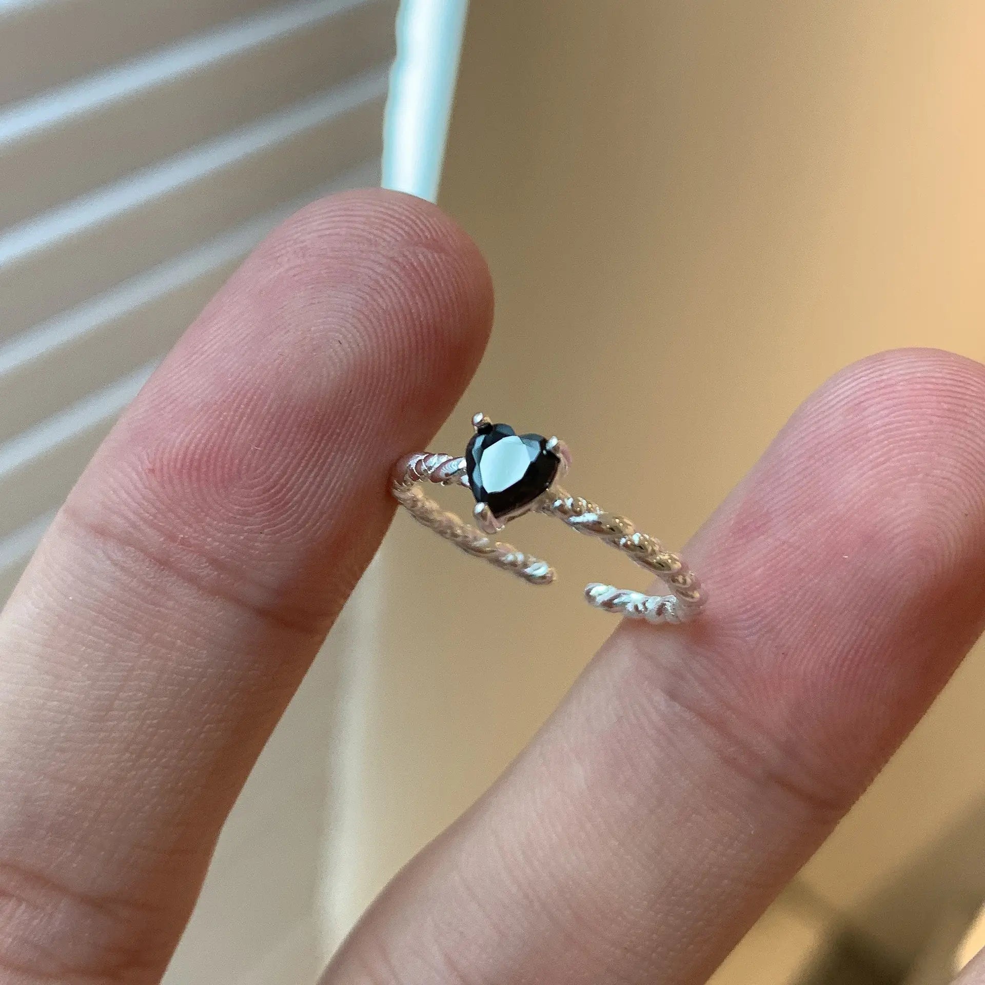 Sterling-silver twist ring with black zirconia centre stone resting between fingers.