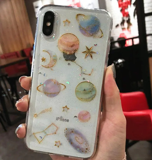 Phone case with celestial designs held by a hand in an indoor setting