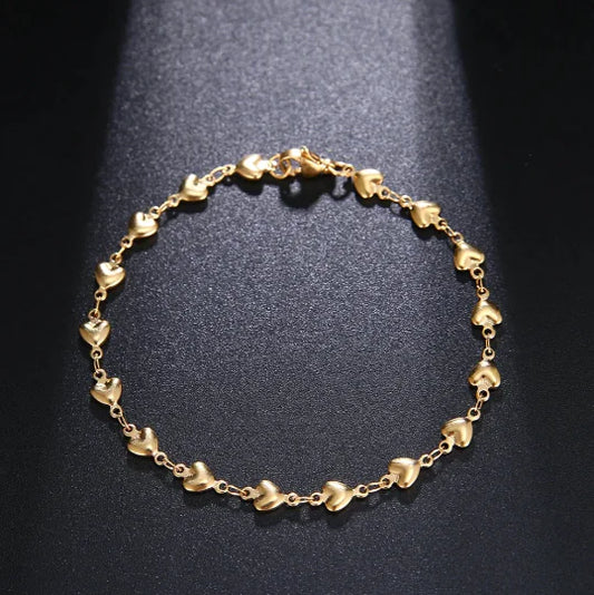 Gold bracelet with heart-shaped links on a dark background