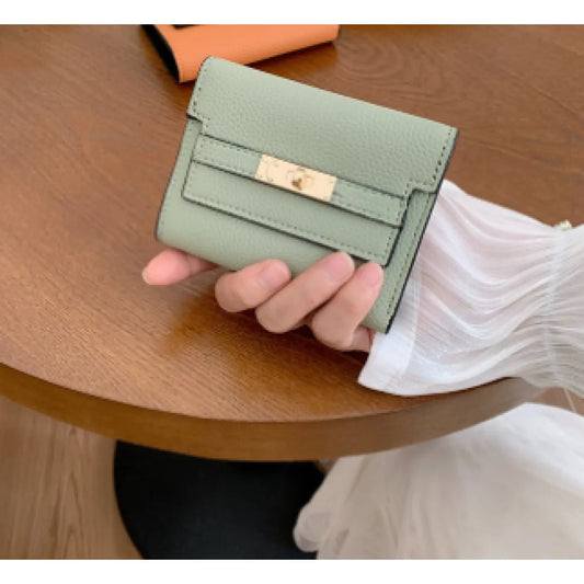 Green wallet held by a hand on a wooden surface