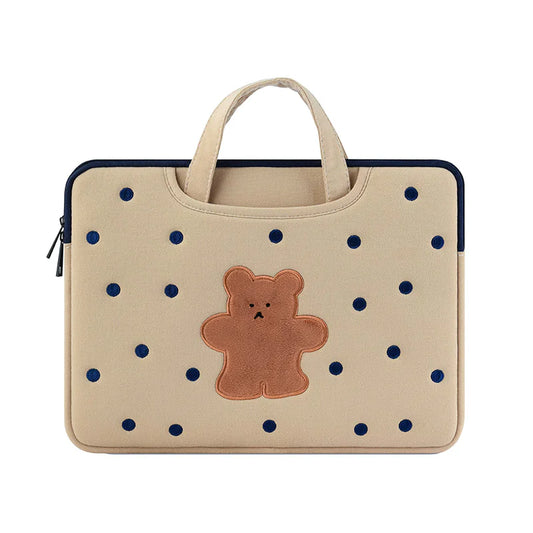 Beige laptop sleeve with blue polka dots and a brown teddy bear patch on a white background