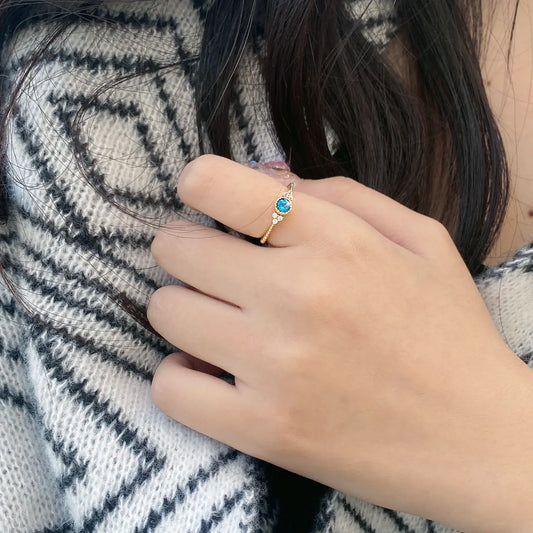 Gold-tone sterling-silver flower ring with blue-colour stone displayed hand