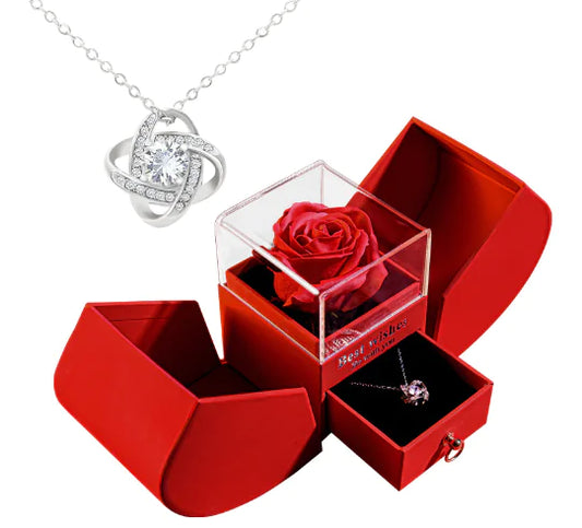 Red jewelry box with a rose, necklace, and ring on a white background