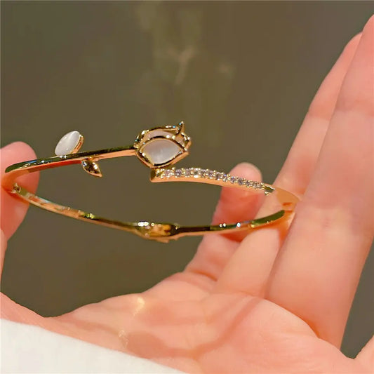 Gold bracelet with gemstones on a hand against a neutral background